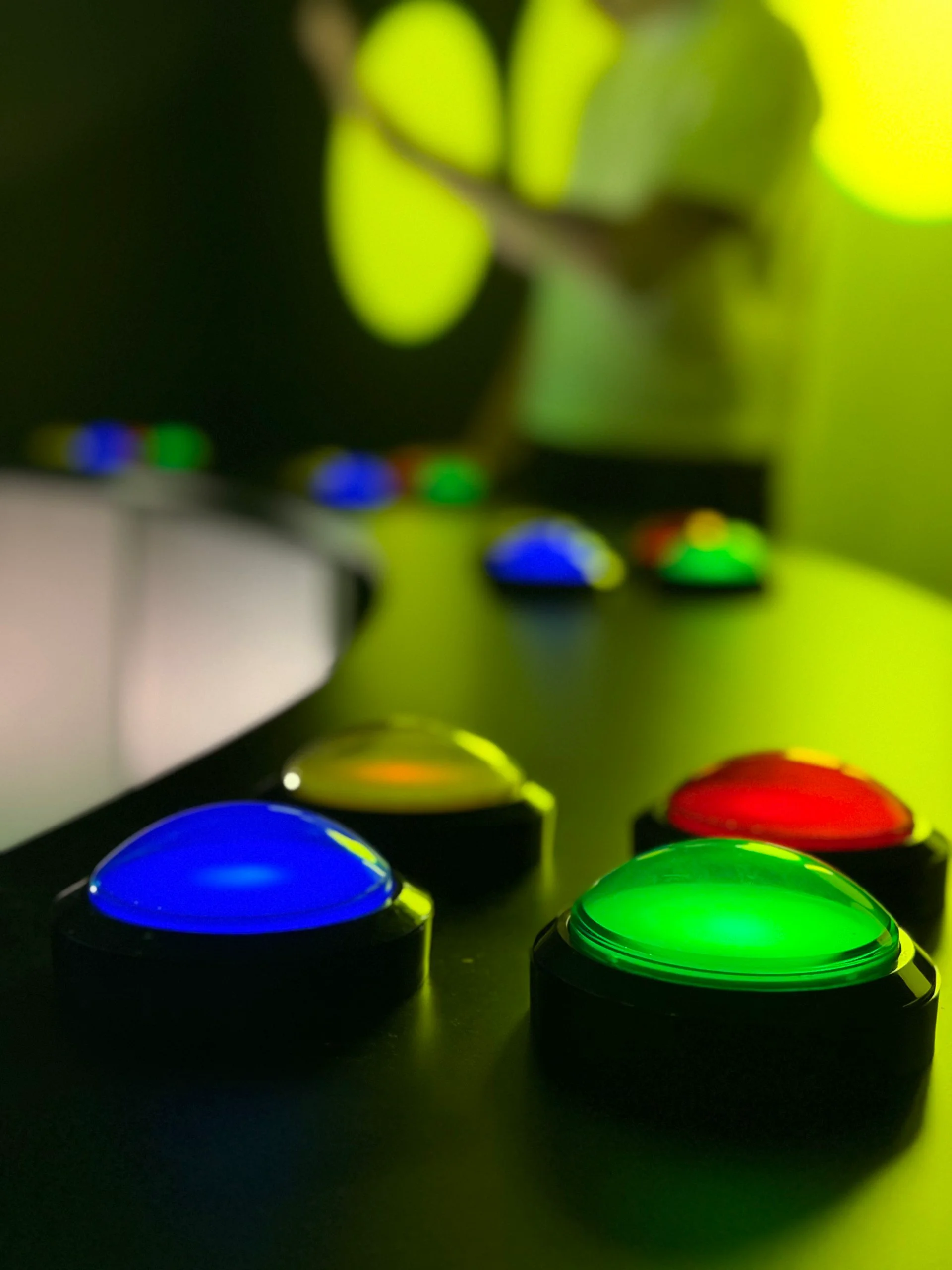 Boutons lumineux bleus, verts, jaunes et rouges sur un panneau sombre.
